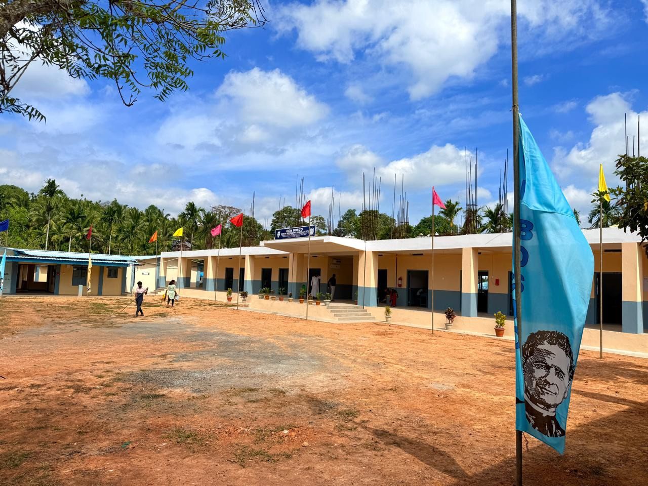 A newly completed single-storey school block with a covered verandah, decorated with flags on its opening day