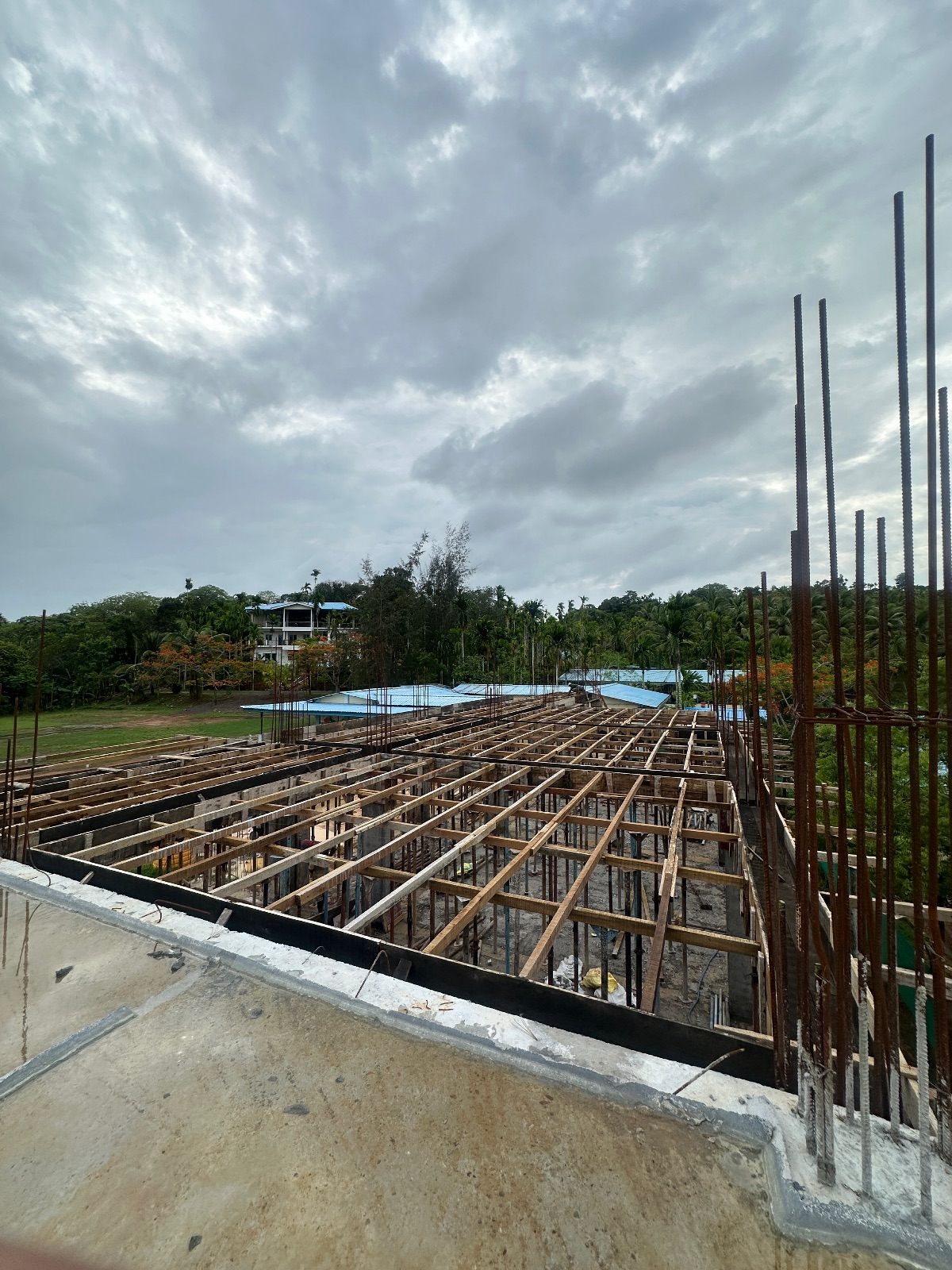 Timber shuttering and props supporting a first-floor slab before concreting, with column starter bars projecting upward