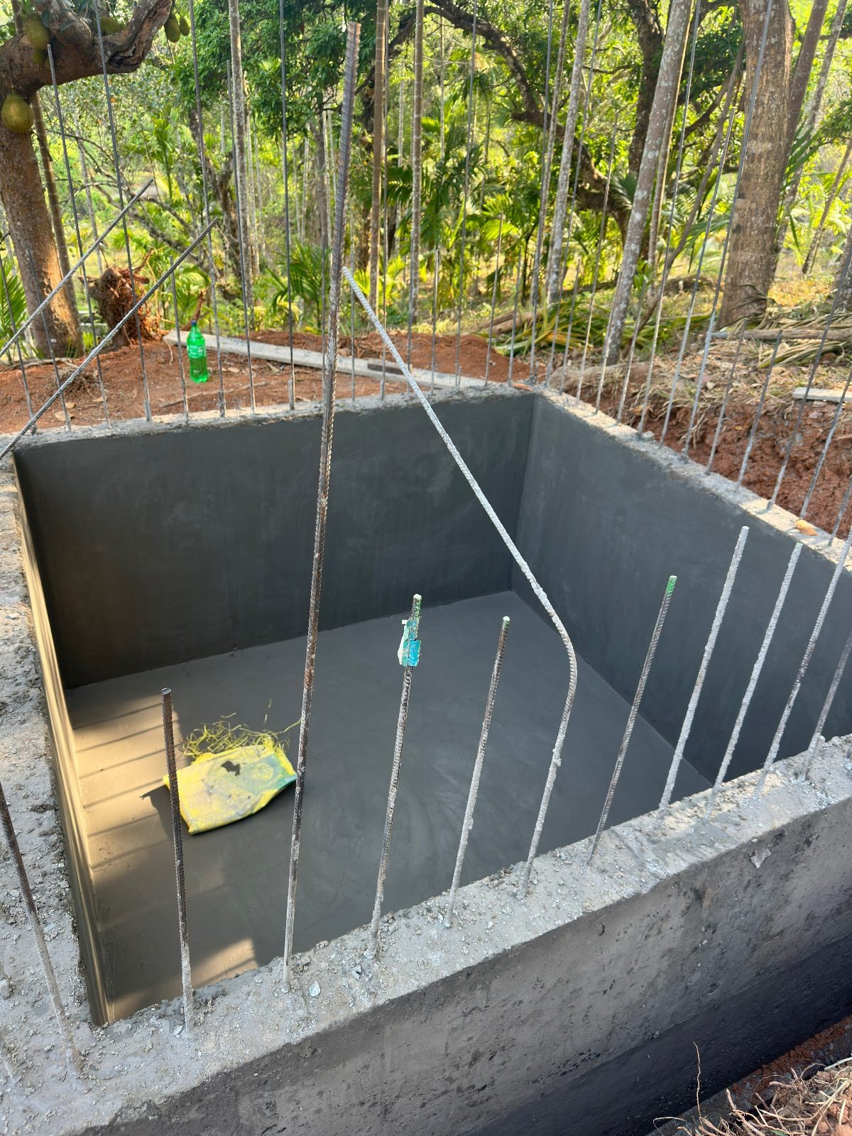 Rectangular underground RCC water tank with smooth waterproof-plastered walls and reinforcement bars around the rim