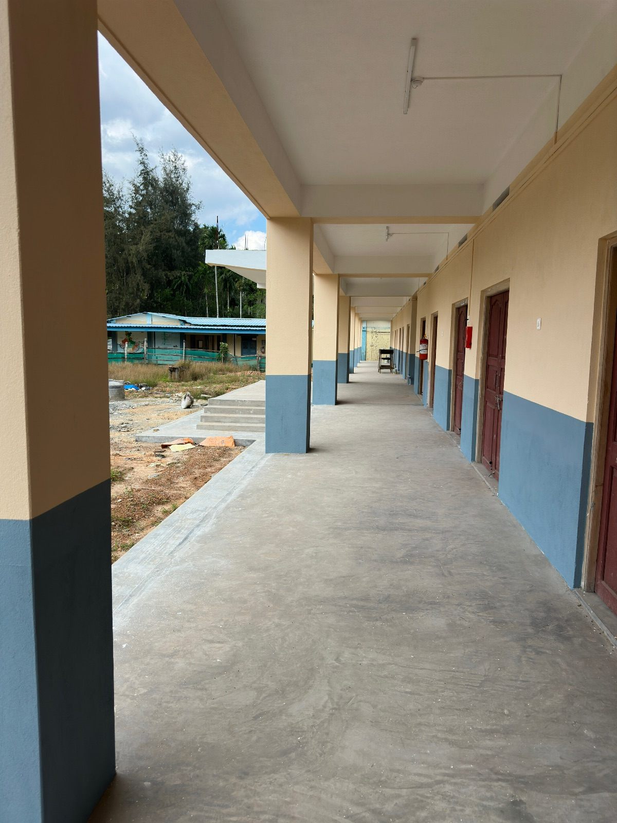Long finished verandah of a classroom block with painted columns, dado band and timber classroom doors
